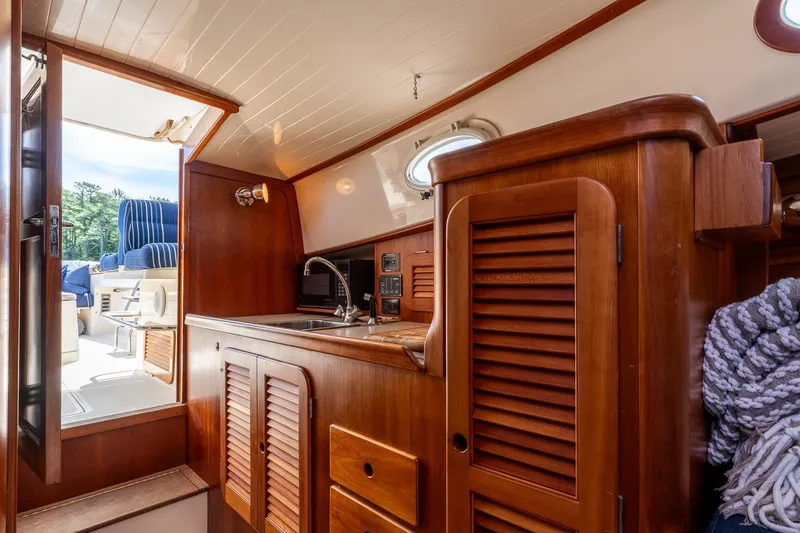 Slide: The Image of Interior of 2000 Hinckley Picnic Boat 36 Classic with wooden cabinetry and compact kitchen area. - 27