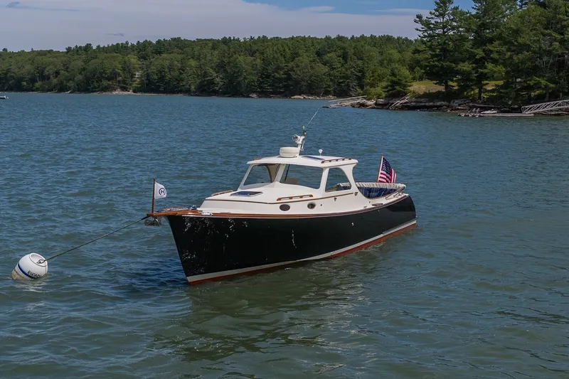 Slide: The Image of 2000 Hinckley Picnic Boat 36 Classic anchored on a serene lake with forested shoreline. - 32