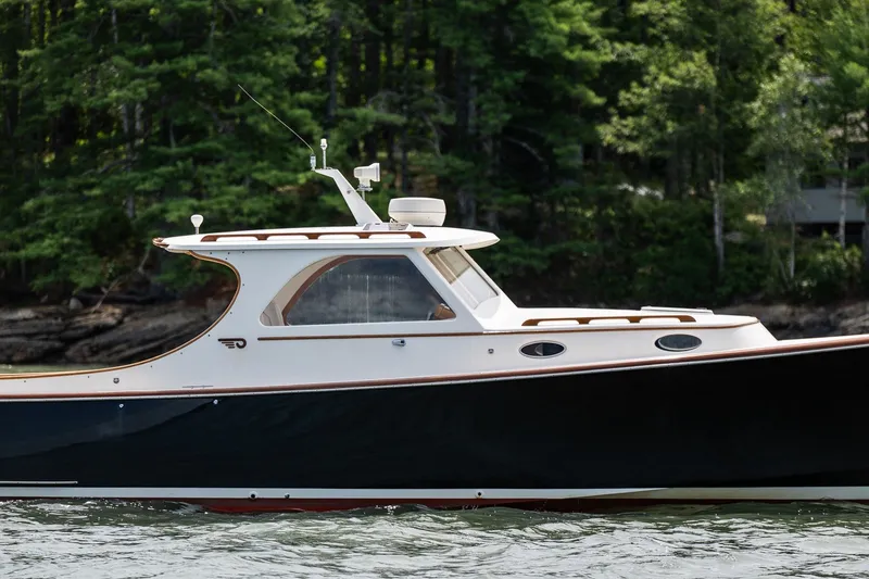 Slide: The Image of 2000 Hinckley Picnic Boat 36 Classic cruising on a serene waterway with lush forest backdrop. - 4