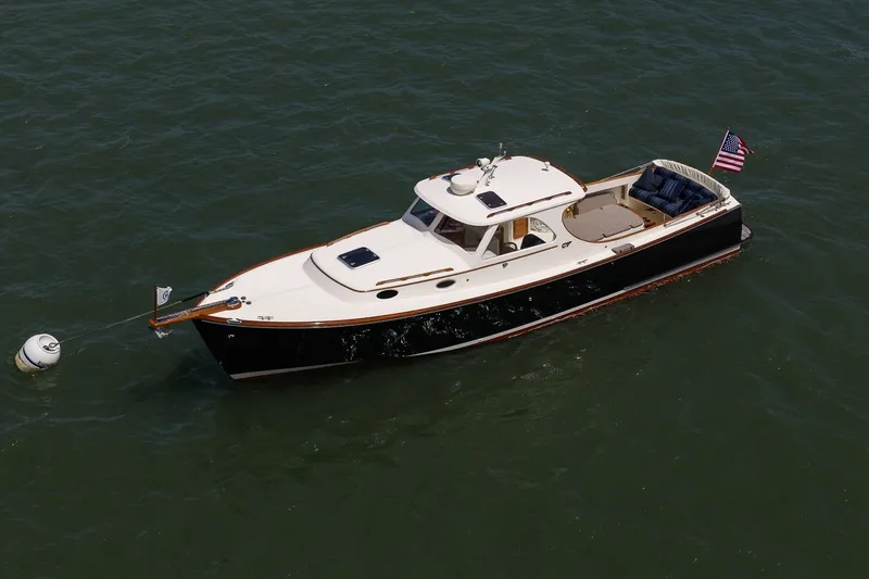Slide: The Image of 2000 Hinckley Picnic Boat 36 Classic on water, featuring elegant design and American flag. - 8
