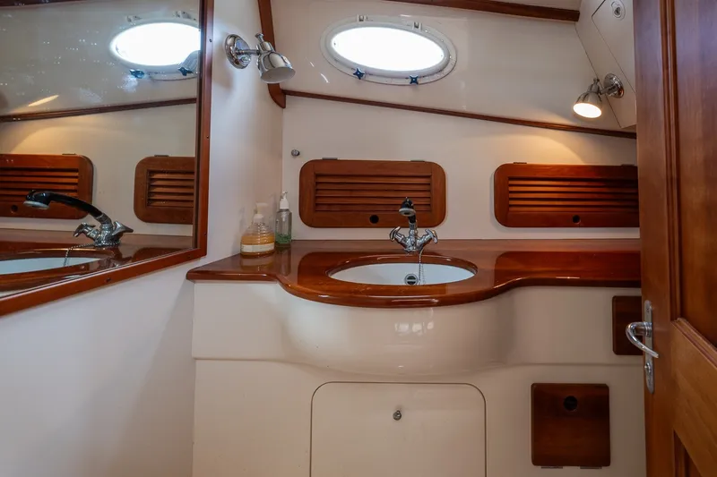 Slide: The Image of Hinckley Picnic Boat 36 Classic 2000 bathroom with wooden accents and porthole window. - 29