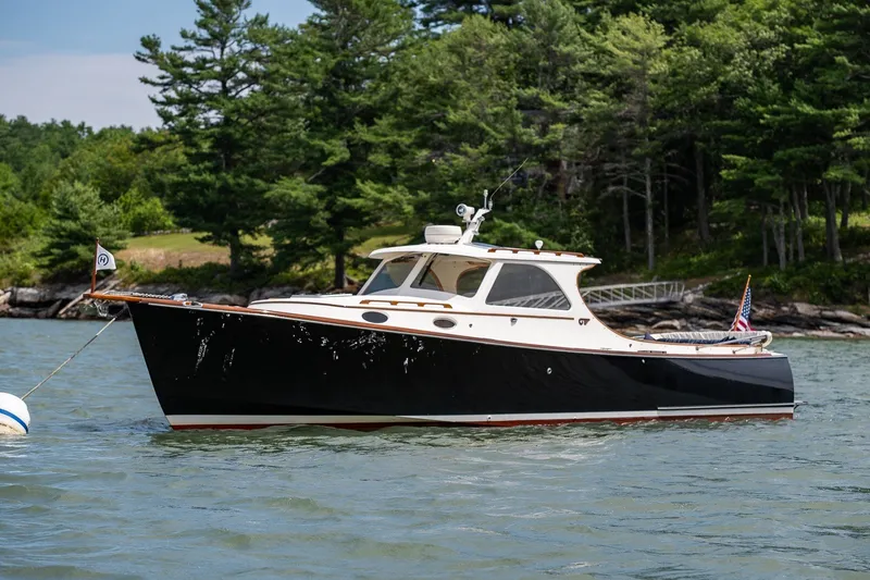 The Image of 2000 Hinckley Picnic Boat 36 Classic on water, surrounded by lush greenery. - 1
