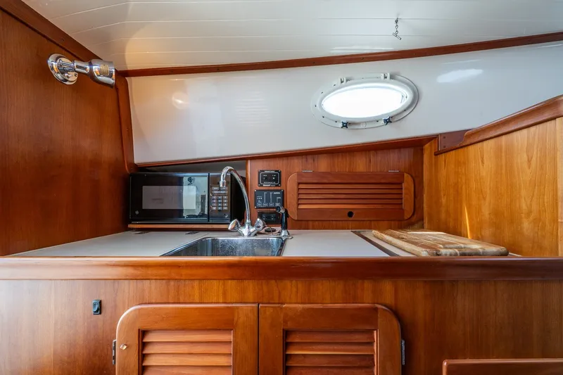 Slide: The Image of 2000 Hinckley Picnic Boat 36 Classic interior with wooden cabinetry and kitchenette. - 26