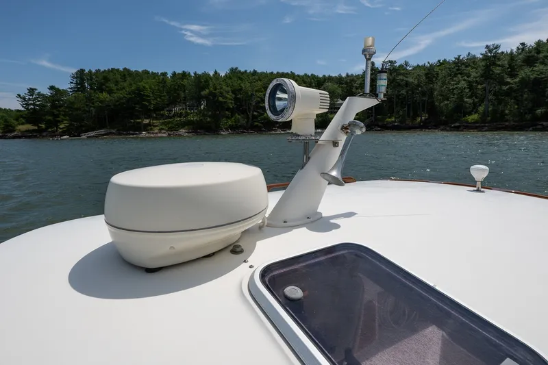 Slide: The Image of Hinckley Picnic Boat 36 Classic 2000, deck view with radar and spotlight, scenic water backdrop. - 12