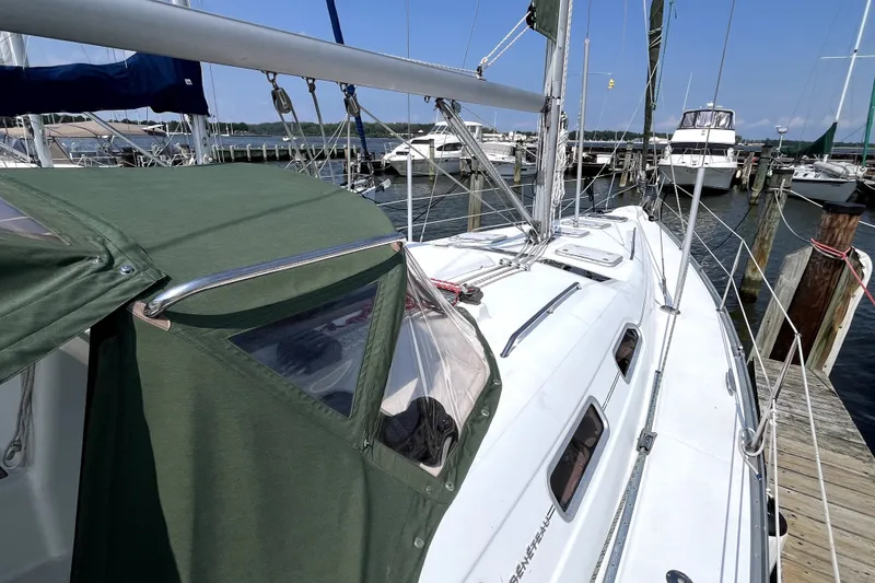 Slide: The Image of 2006 Beneteau Oceanis 393 sailboat docked at marina, featuring green canopy and sleek design. - 59