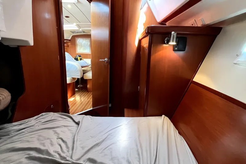 Slide: The Image of Interior cabin of 2006 Beneteau Oceanis 393 yacht, featuring wooden finishes and cozy bedding. - 29