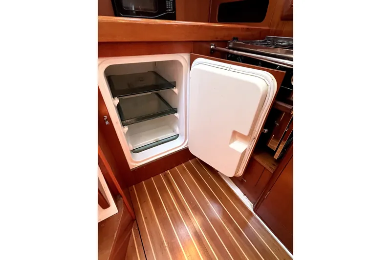 Slide: The Image of Open refrigerator in 2006 Beneteau Oceanis 393 yacht kitchen, featuring wooden flooring and cabinetry. - 23