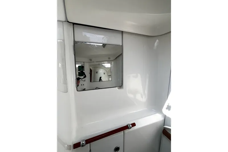 Slide: The Image of Interior of 2006 Beneteau Oceanis 393 yacht, featuring a sleek white bathroom with mirror. - 52