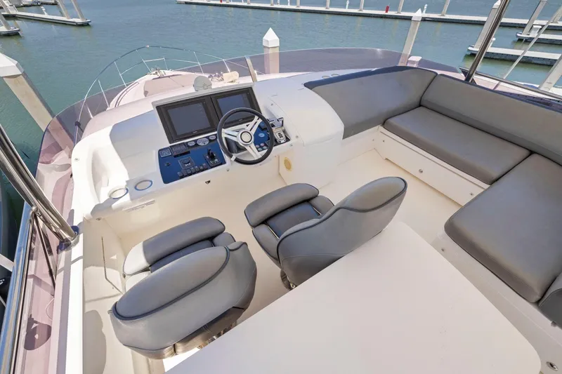 Slide: The Image of Flybridge of 2015 Princess 60 Motor Yacht with helm, seating, and marina view. - 57