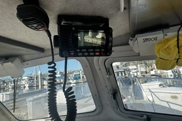 Slide: The Image of Interior view of a 2022 Defiance Admiral 250 EX boat with marine radio and docked boats outside. - 13