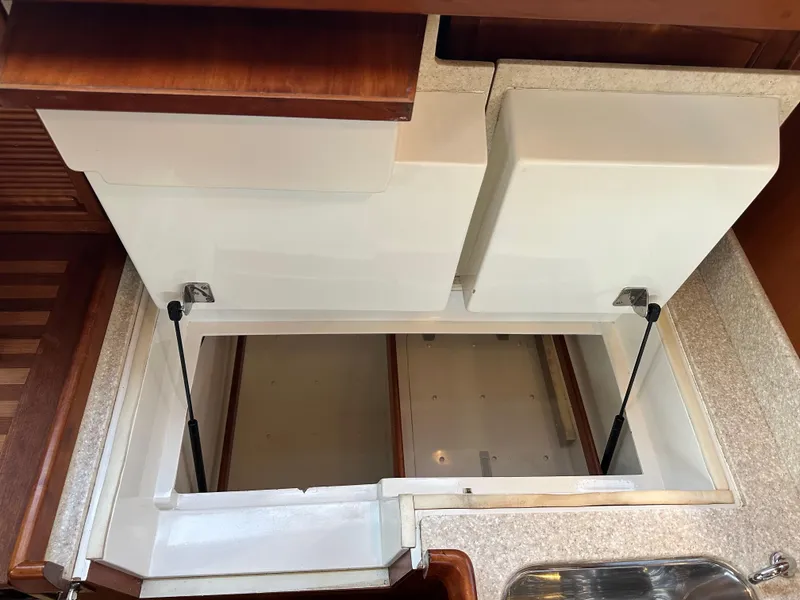 Slide: The Image of Open storage compartment in 2008 Outbound 46 yacht interior, featuring hydraulic supports and wooden finish. - 43