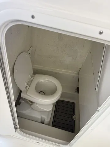 Slide: The Image of The image shows a small, white boat toilet with a seat and a floor mat. - 14