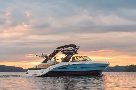 The Image of 2026 Sea Ray SDX 250 Surf boat cruising on a serene lake at sunset. - 1