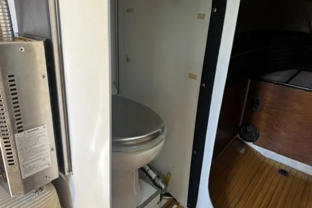 Slide: The Image of Interior of a 1973 Custom BILL LEE 40 yacht featuring a compact bathroom with a stainless steel toilet. - 26