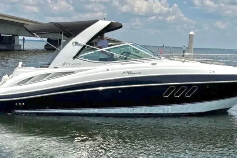 The Image of 2009 Cruisers Yachts 330 Express boat on water near a dock, under a cloudy sky. - 0