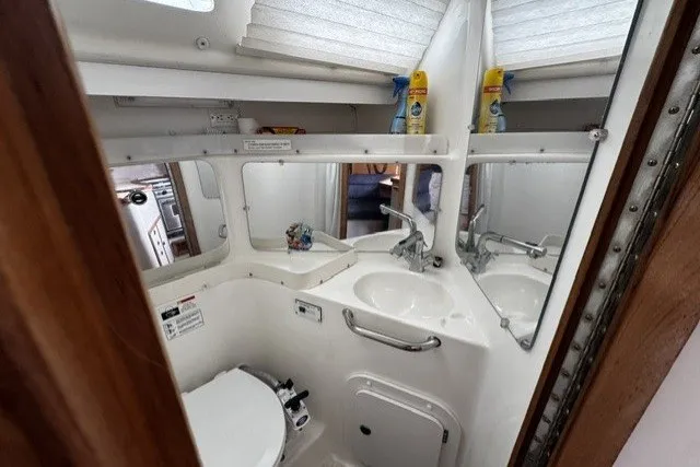 Slide: The Image of Compact bathroom in a 2000 Catalina 320 sailboat, featuring a sink, toilet, and mirror. - 13