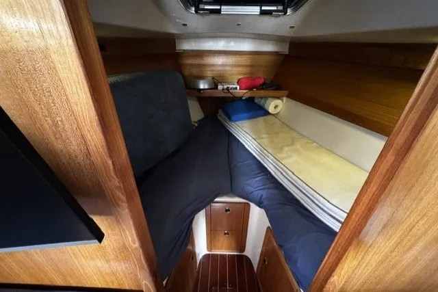 Slide: The Image of Cozy cabin interior of a 2000 Catalina 320 sailboat with wooden finishes and bedding. - 18
