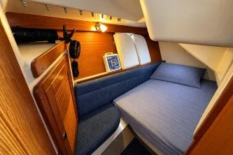 Slide: The Image of Cozy cabin interior of a 2000 Catalina 320 sailboat with wooden accents and blue bedding. - 19