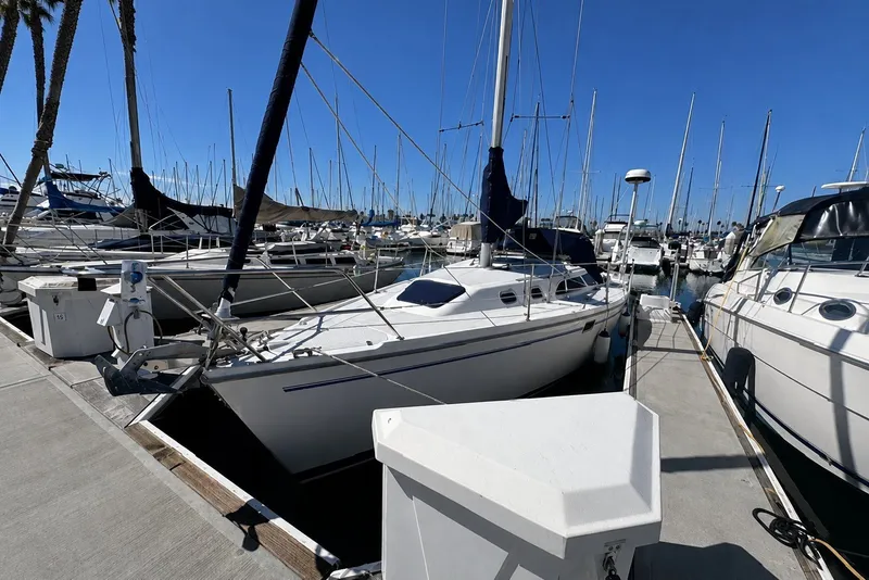 Slide: The Image of 2000 Catalina 320 sailboat docked at a marina under clear blue skies. - 1