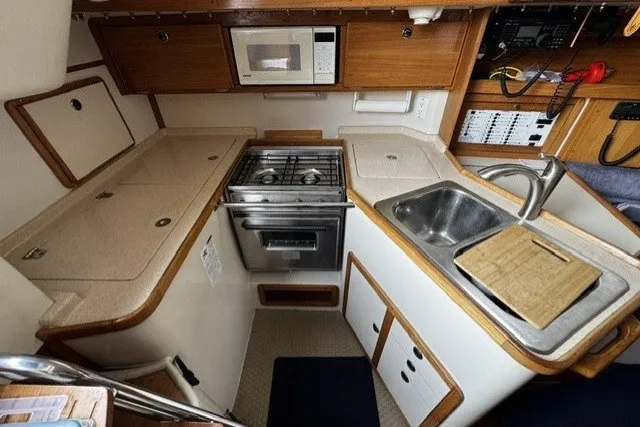 Slide: The Image of Compact kitchen in a 2000 Catalina 320 sailboat with stove, sink, and microwave. - 27