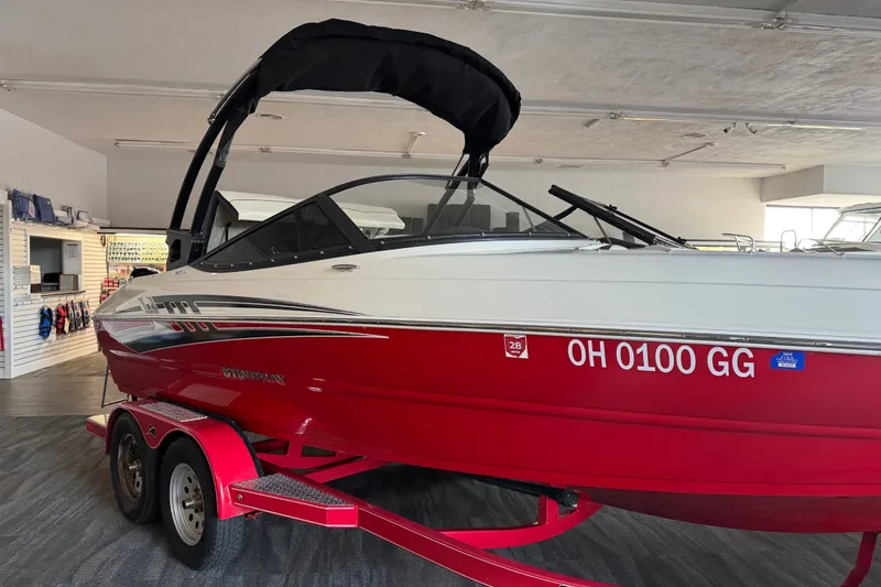 Slide: The Image of 2021 Stingray 208 LR boat in showroom, red hull, black canopy, on trailer. - 7