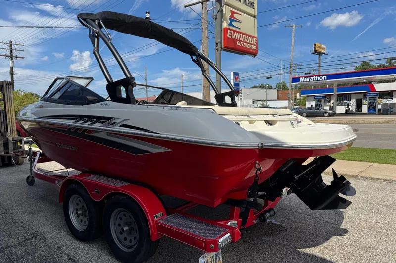 Slide: The Image of 2021 Stingray 208 LR boat on trailer, parked near a gas station under a clear blue sky. - 1