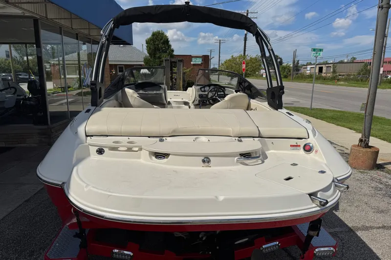 Slide: The Image of 2021 Stingray 208 LR boat with beige seating, parked outdoors on a sunny day. - 2