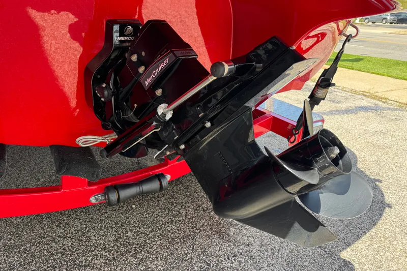 Slide: The Image of 2021 Stingray 208 LR boat with MerCruiser outdrive, red hull, parked on pavement. - 3