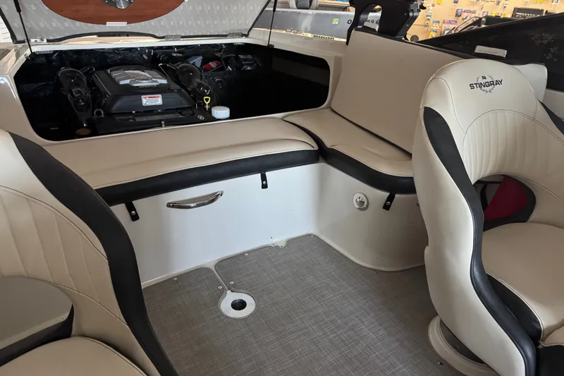 Slide: The Image of Interior of a 2021 Stingray 208 LR boat, featuring beige seating and engine compartment. - 10