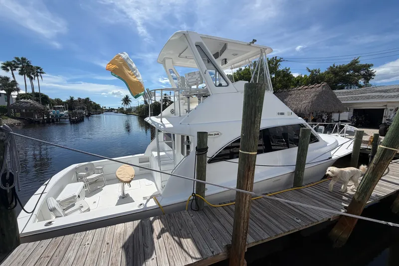 Slide: The Image of Fifth Ocean Yachts 40, 1997 model, docked by a scenic canal with a dog nearby. - 1
