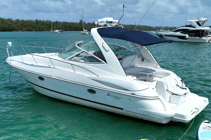 Slide: The Image of 2001 Cruisers Yachts 3470 Express in serene waters, featuring sleek design and blue canopy. - 2