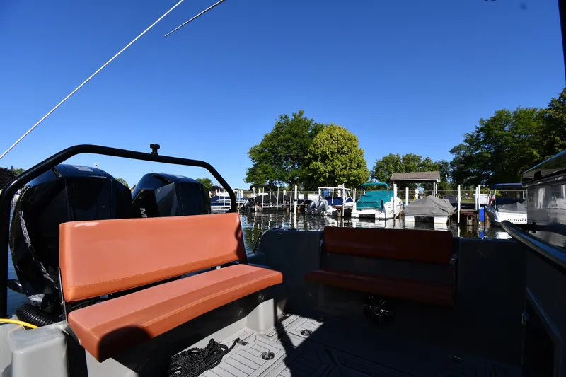 Slide: The Image of 2020 Dromeas D28 CC boat interior with brown seating, docked at a marina under clear blue skies. - 15