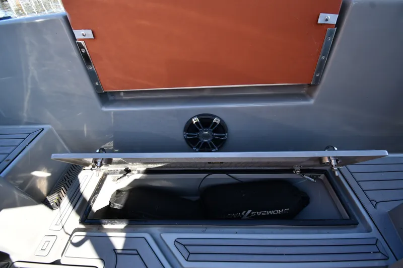 Slide: The Image of Open storage compartment on 2020 Dromeas D28 CC boat, featuring sleek design and speaker. - 28