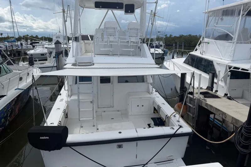 Slide: The Image of 1999 Phoenix 38 SFX Convertible yacht docked at marina, featuring spacious deck and seating area. - 4