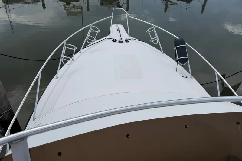 Slide: The Image of Bow view of a 1999 Phoenix 38 SFX Convertible boat docked in calm waters. - 55