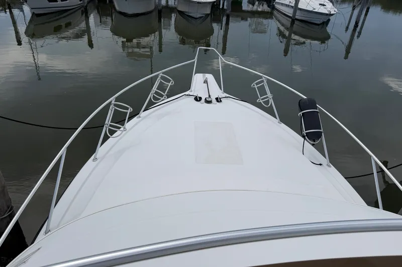 Slide: The Image of Bow view of a 1999 Phoenix 38 SFX Convertible yacht docked in a marina. - 56