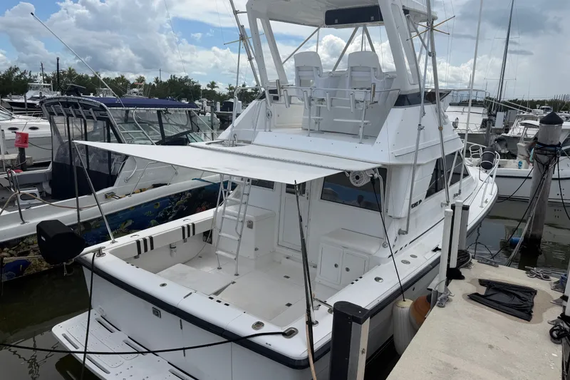 Slide: The Image of 1999 Phoenix 38 SFX Convertible yacht docked at marina under cloudy sky. - 6