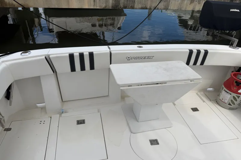 Slide: The Image of 1999 Phoenix 38 SFX Convertible boat deck with seating and table, docked by the water. - 10