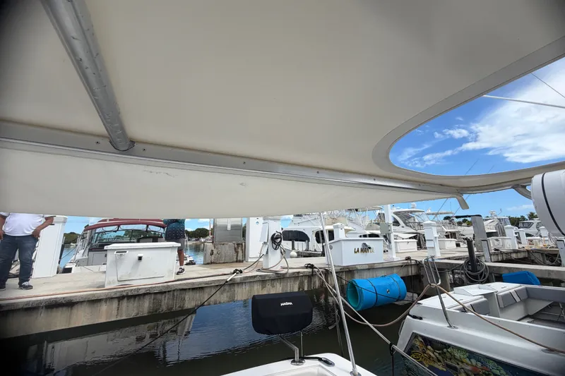 Slide: The Image of Docked 1999 Phoenix 38 SFX Convertible boat under canopy, marina view. - 25