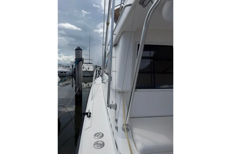 Slide: The Image of Side view of a 1999 Phoenix 38 SFX Convertible yacht docked at a marina. - 20