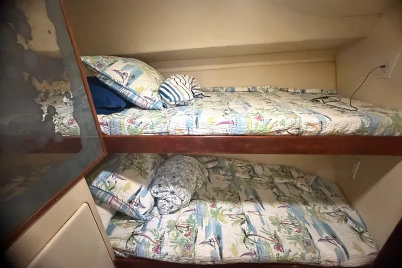 Slide: The Image of Bunk beds in a 1999 Phoenix 38 SFX Convertible boat cabin with nautical-themed bedding. - 48