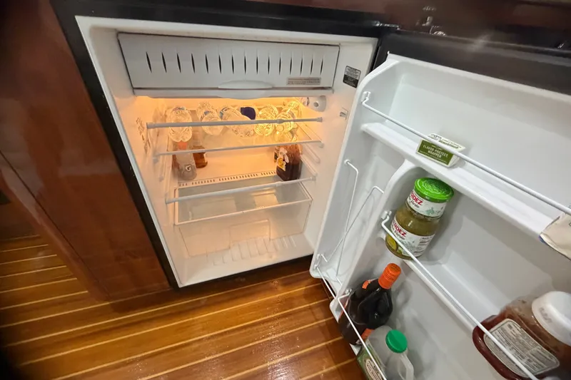 Slide: The Image of Open refrigerator on Phoenix 38 SFX Convertible yacht, stocked with beverages and condiments. - 32