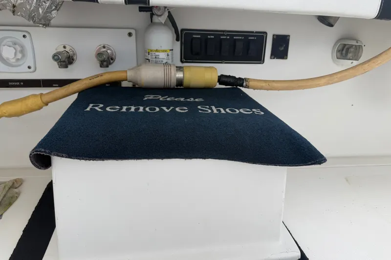 Slide: The Image of Phoenix 38 SFX Convertible 1999 boat interior with 'Please Remove Shoes' mat and cables. - 14