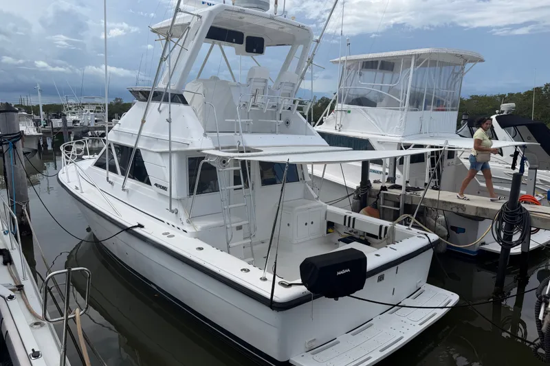 The Image of 1999 Phoenix 38 SFX Convertible yacht docked at marina under cloudy sky. - 1
