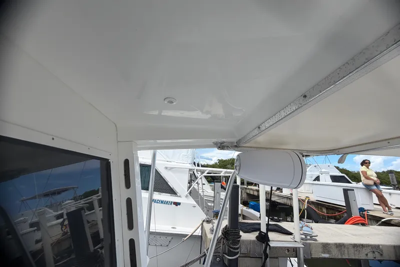 Slide: The Image of 1999 Phoenix 38 SFX Convertible boat docked, featuring interior view and marina surroundings. - 23