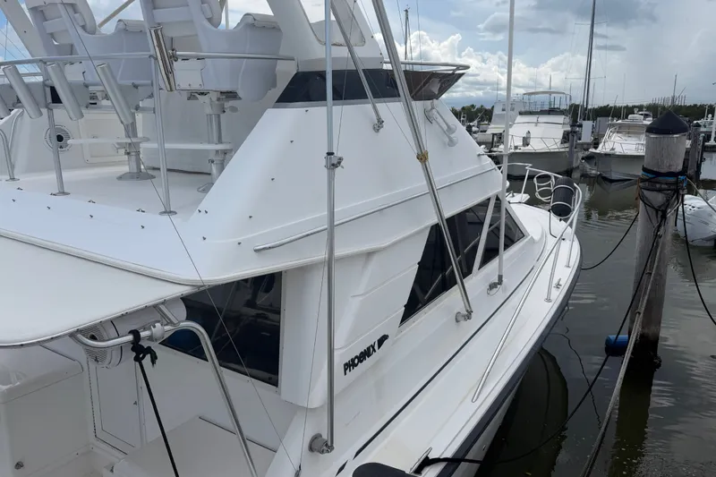 Slide: The Image of 1999 Phoenix 38 SFX Convertible yacht docked at marina, showcasing sleek design and spacious deck. - 7