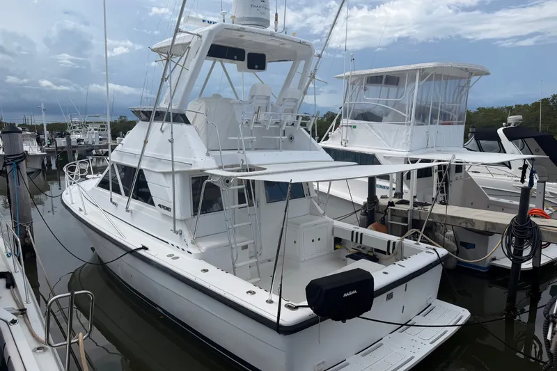 Slide: The Image of 1999 Phoenix 38 SFX Convertible yacht docked at marina under cloudy sky. - 2