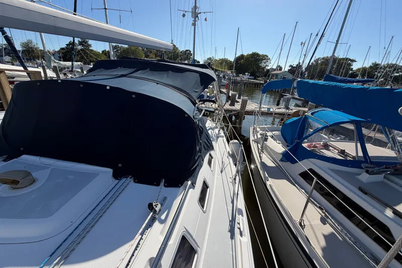 Slide: The Image of 2002 Hunter 356 sailboat docked at marina, featuring blue canopy and clear skies. - 11