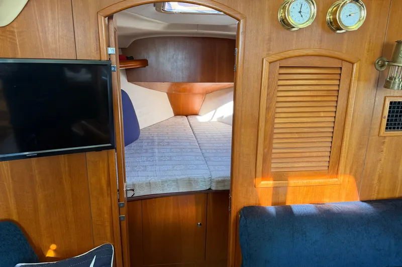 Slide: The Image of Interior of a 2002 Hunter 356 sailboat cabin with bed, TV, and wooden paneling. - 42