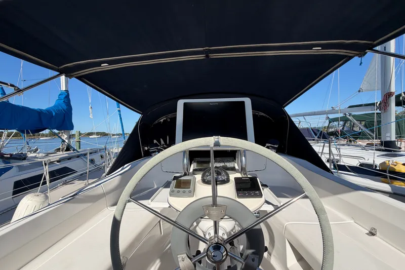 Slide: The Image of Steering wheel of a 2002 Hunter 356 sailboat, docked with clear blue skies. - 14